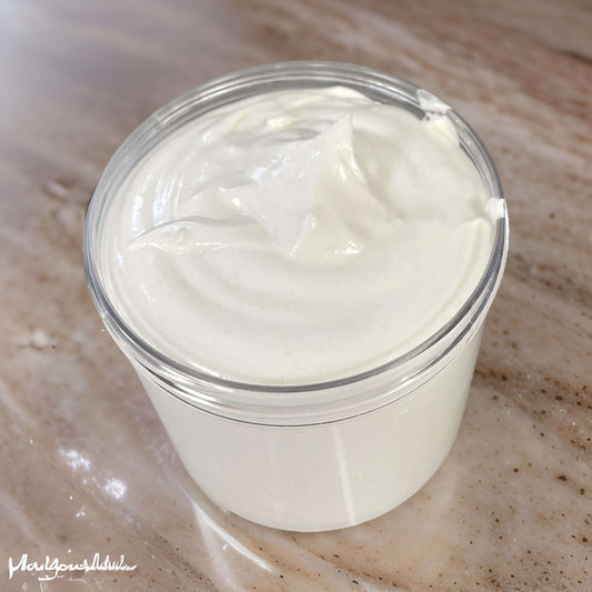Whipped body butters in a clear container, creamy texture, vegan and paraben-free formula.
