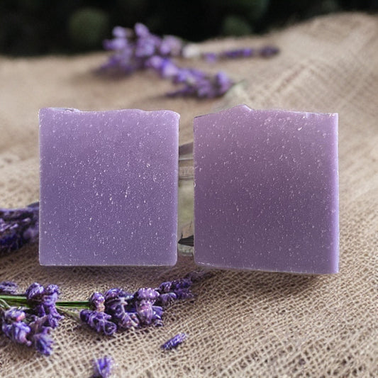 Organic lavender soap bars surrounded by dried lavender flowers on a rustic surface.