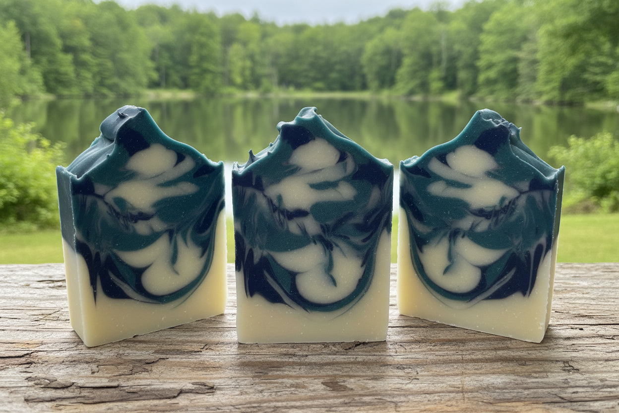 Midnight Timber soap bars with navy blue and white swirls against a serene natural backdrop.