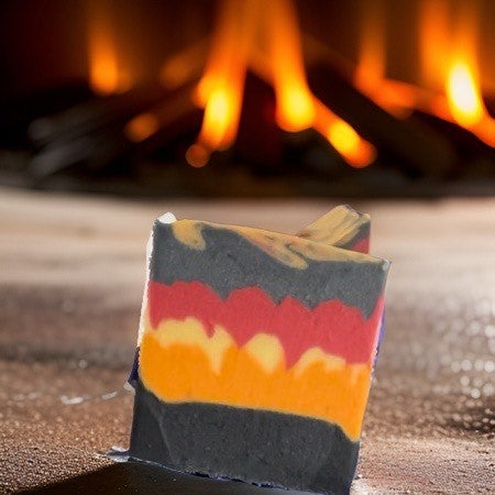 Vegan Campfire Soap bar with vibrant colors in front of a cozy campfire, showcasing its organic and inviting nature.