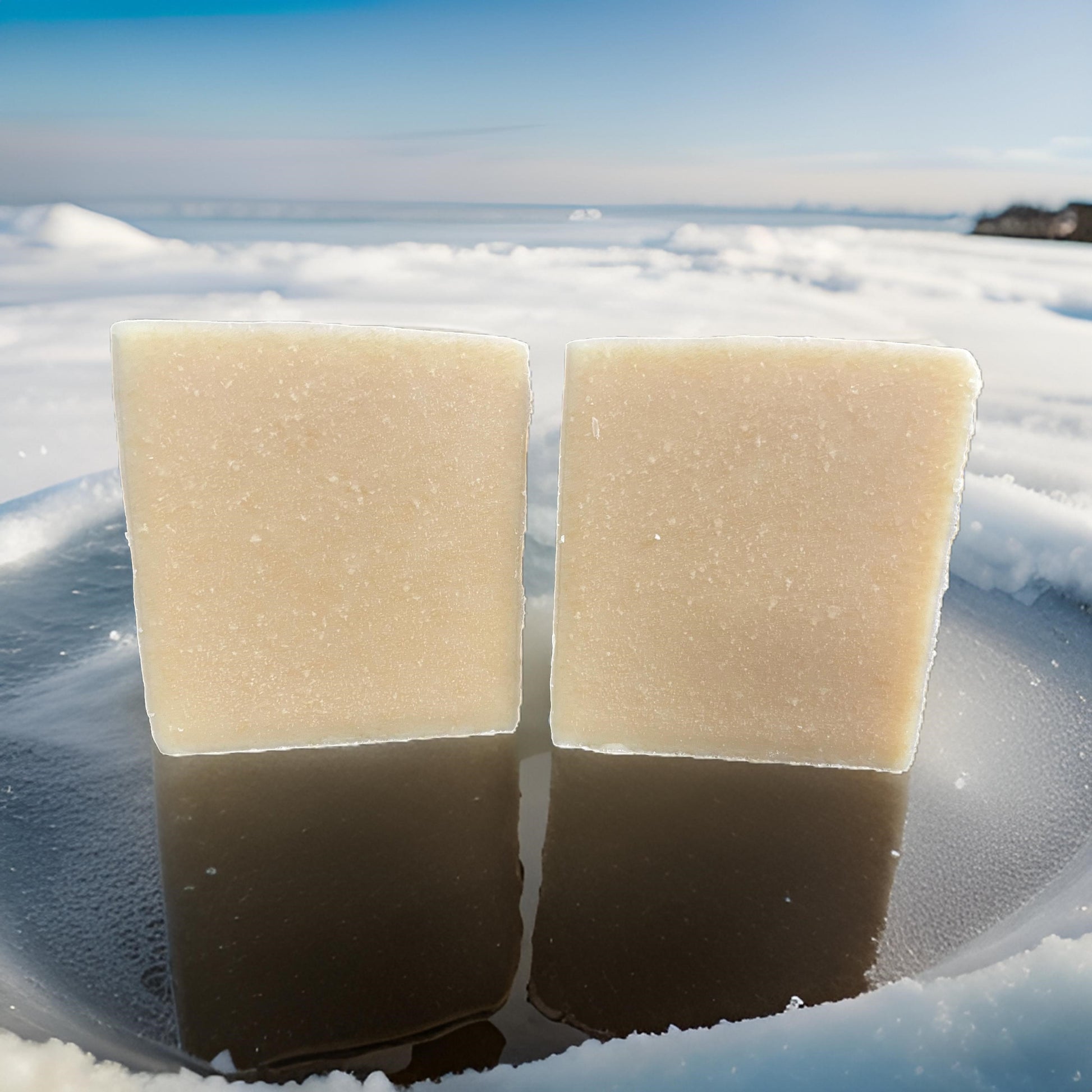 Two bars of Organic Beef Tallow Soap-Purely displayed on a reflective surface in a snowy outdoor setting.