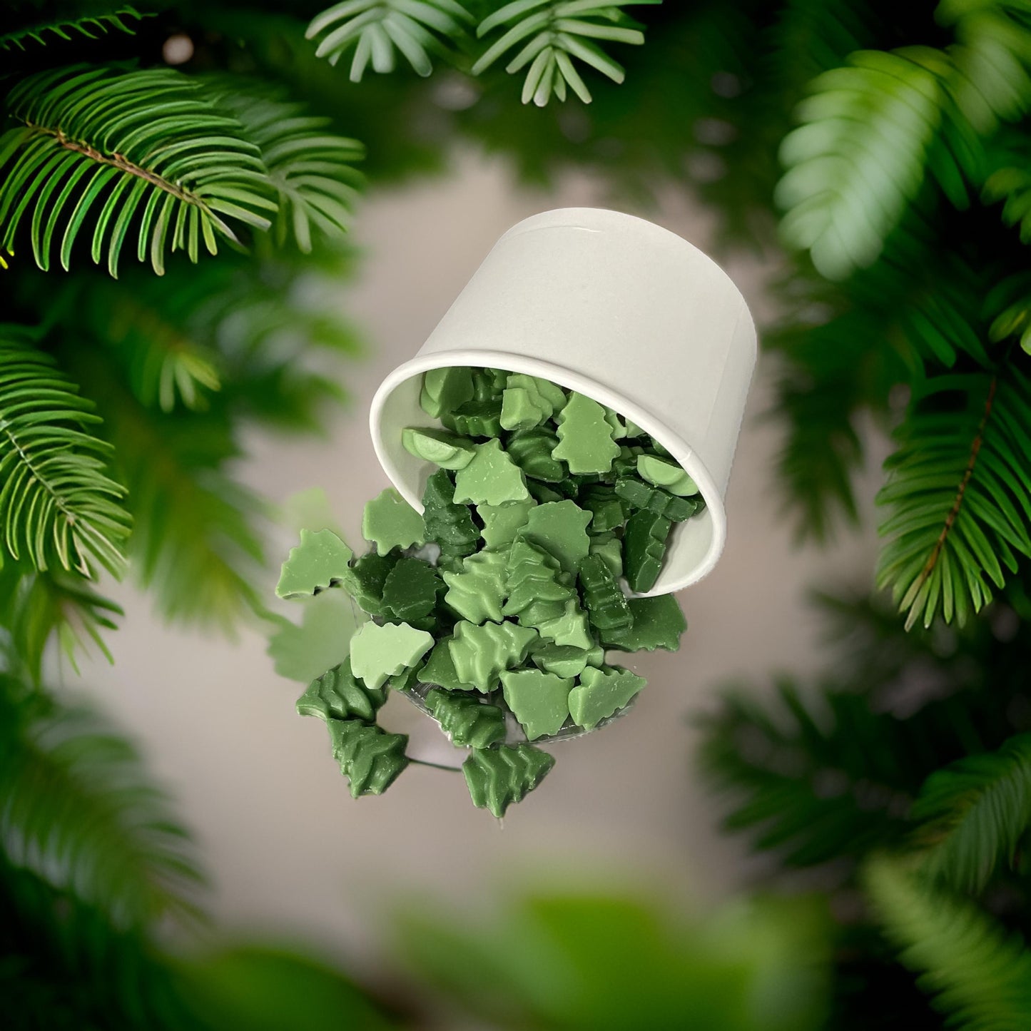 Trees for Autism wax melts in a white cup among green foliage, offering a balsam scent for charity.