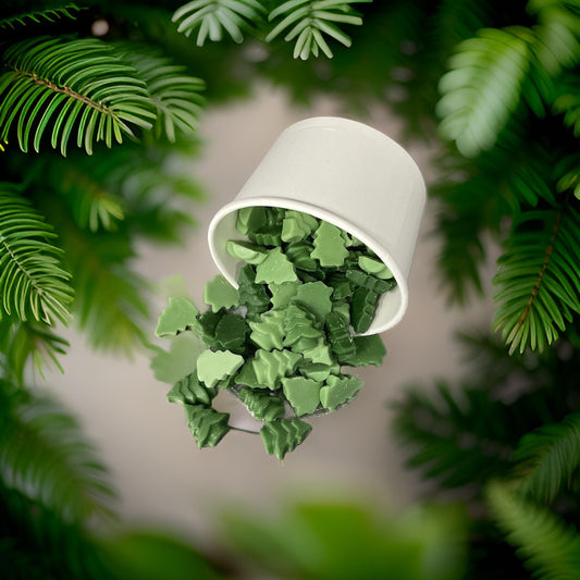 Trees for Autism wax melts in a white cup among green foliage, offering a balsam scent for charity.