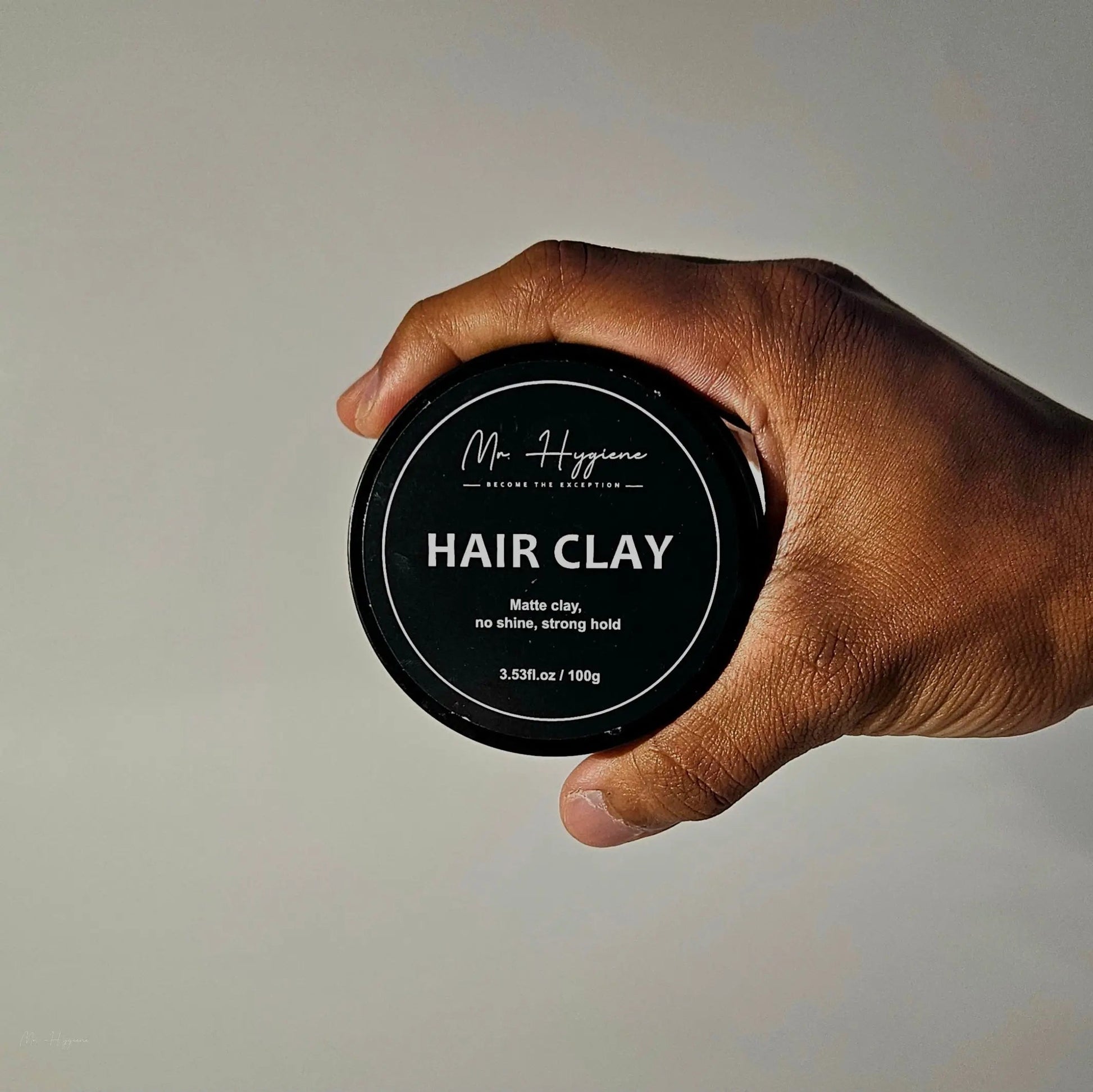 Hand holding a jar of Matte Finish Hair Clay with strong hold and no shine.
