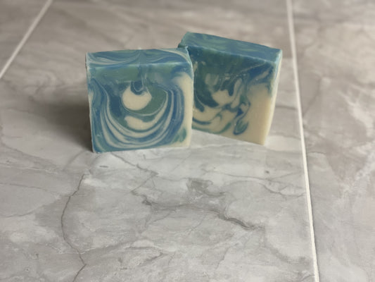 Two bars of Glacier Falls soap with blue and white swirls on a gray marble surface.